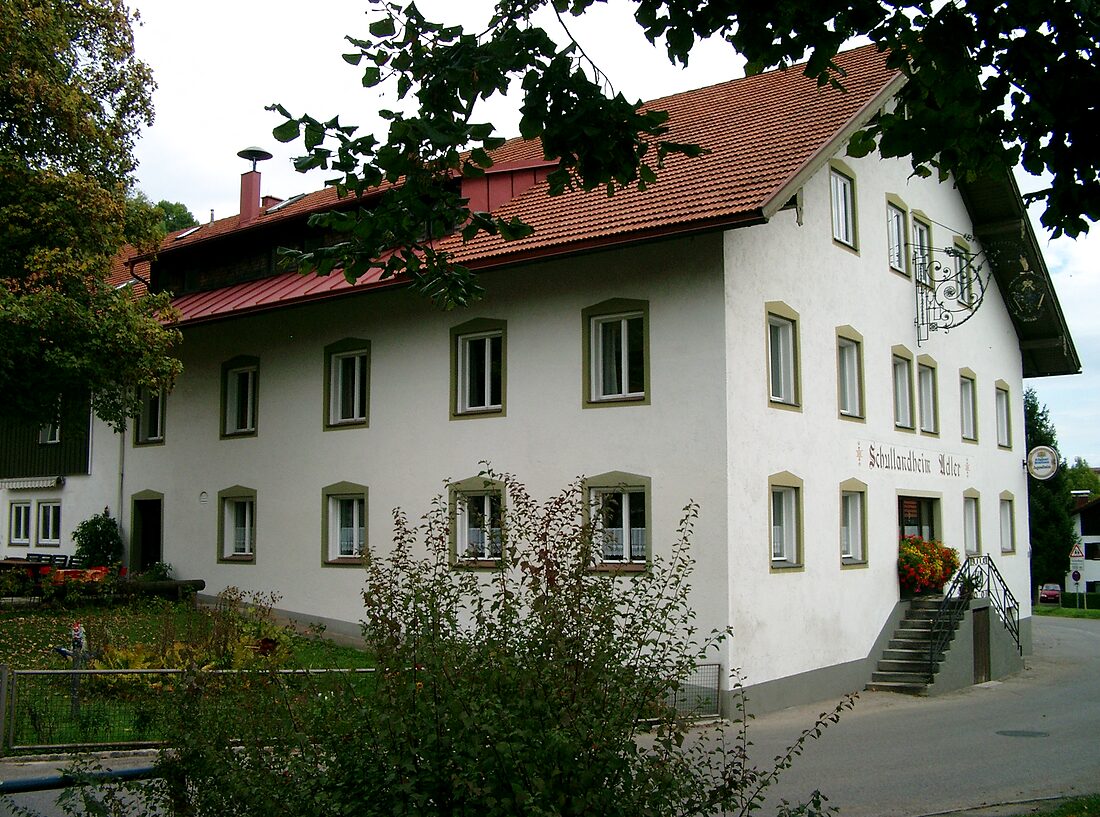 Außenansicht des Schullandheims Adler – ein weißes Allgäuer Haus mit rotem Ziegeldach, Schriftzug und Wappen-Schild an der Fassade