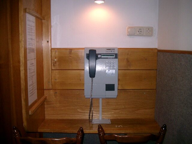 Wandmontierter Münzfernsprecher (Gästetelefon) an einer Holzvertäfelung
