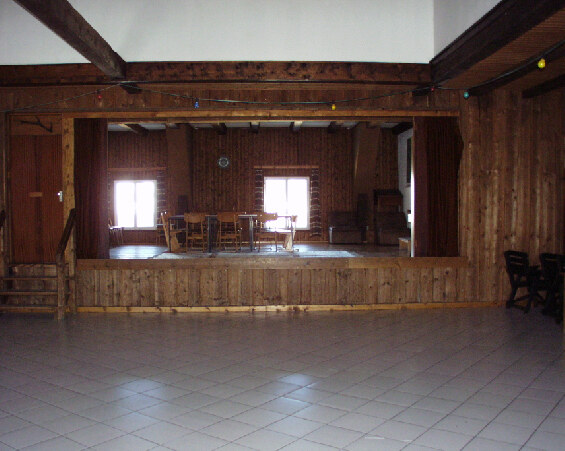 Großer Saal mit erhöhter Holzbühne und weiter Bodenfläche